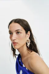 Pendientes metálicos dorados con diseño de hojas en la parte superior y colgantes en forma de gota con acabado nacarado.