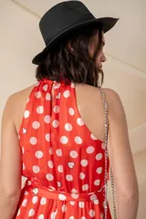 Vestido midi de gasa con seda, color rojo con lunares blancos, cuello halter, cintura elastizada con lazo y volado en el ruedo.