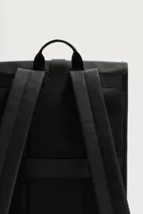 Mochila de diseño minimalista en acabado engomado color negro. Cuenta con compartimento principal con cierre de solapa y hebilla de liberación rápida, bolsillo frontal con cierre, compartimento interno para dispositivos electrónicos y espalda acolchada con banda de sujeción para equipaje.
