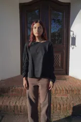 Remera negra de mangas largas con detalle de frunce en una manga y drapeado en el hombro.