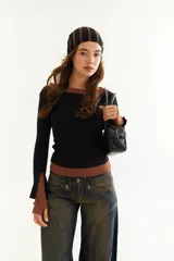 Top de manga larga con diseño de doble capa superpuesta, combinando una capa superior negra y una inferior marrón. Presenta cuello redondo, ajuste al cuerpo y detalle de bordado BG en la parte inferior.