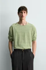 Camiseta de manga larga con ajuste relaxed fit y cuello redondo amplio, confeccionada en tejido de mezcla de algodón y lino con patrón de rayas horizontales en color verde y blanco.