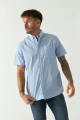 Camisa de manga corta con cuello abotonado, cierre frontal con botones y bolsillo en el pecho con logo bordado. Confeccionada en algodón con un sutil estampado de microcuadros.