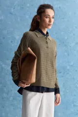 Sweater de punto color verde militar, con cuello polo y cierre frontal de botones, de manga larga con puños elastizados y diseño texturizado con relieve geométrico.
