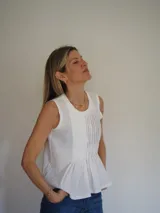 Blusa sin mangas de algodón color blanco, con delicadas tablas en el frente y terminaciones levemente desflecadas, de corte suelto y liviano.
