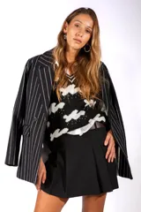 Chaqueta tipo blazer de corte sastre, color negro con diseño de rayas verticales blancas. Presenta solapas clásicas, cierre frontal con botones y hombreras estructuradas.