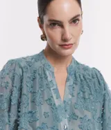 Camisa celeste en tejido chiffon con textura de bordado con felpas, cuello mao, abotonadura frontal y mangas largas abullonadas.