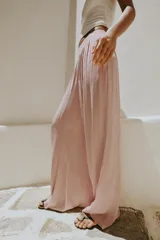 Pantalón fluido de tiro alto con cintura elástica y pernera ancha, de color rosado.