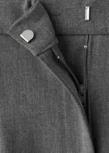 Pantalón de vestir gris de tiro medio, con diseño recto y largo, detalle de pinzas frontales y dos bolsillos laterales. Cuenta con cierre oculto de botón, gancho y cremallera.