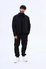 Campera negra con cuello de corderito sintético, cierre frontal con botones y bolsillos laterales. Diseño de corte recto y estructura resistente.