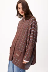 Sweater de tejido artesanal con diseño de rayas verticales en tonos camel y beige, corte holgado, cuello redondo y puños altos ajustados.