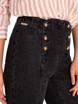 Jeans de denim gris oscuro, estilo bootcut de tiro alto, con costuras frontales verticales que estilizan la pierna y cierre de doble botonadura metálica en la parte delantera.
