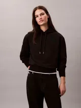 Buzo con capucha Calvin Klein de corte clásico, confeccionado en mezcla de algodón y poliéster. Presenta cordones ajustables en la capucha, puños y dobladillo con terminación en punto canalé, y el logotipo de la marca bordado de forma sutil en el pecho.