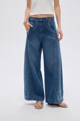 Pantalón jean azul de tiro alto, corte baggy y piernas anchas, con costuras decorativas frontales.