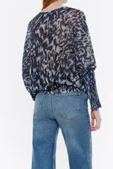 Jersey de lúrex negro con estampado de manchas rojas, escote redondo y manga larga murciélago con puño ajustado.