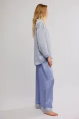 Conjunto de pijama de dos piezas, compuesto por una camisa de manga larga con estampado geométrico, cuello y botonadura frontal, y un pantalón largo fluido de color celeste con cintura elastizada, cordón de ajuste y detalles estampados en los dobladillos.