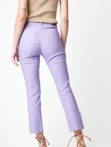Pantalón de gabardina elastizada color lila, de pierna recta con largo arriba del tobillo y tajos en el ruedo. Tiene cierre delantero, botón, bolsillos laterales y traseros.