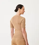 Blusa color beige en tejido de punto acanalado, con cuello polo y cremallera.