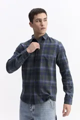 Camisa de manga larga confeccionada en viyela de algodón con diseño de cuadros en tonos azul y verde. Presenta cierre frontal con botones, cuello clásico y bolsillo en el pecho.