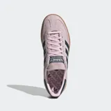 Championes Adidas modelo Handball Spezial, confeccionados en gamuza color rosado con las icónicas tres tiras y detalle en el talón en color azul oscuro. Presentan puntera en forma de T y suela de caucho color caramelo.