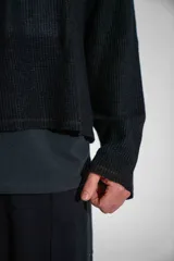 Buzo de tejido de punto fino en color negro, con diseño de cuello redondo y corte holgado. Presenta un estampado gráfico estilo gótico en el centro del pecho.