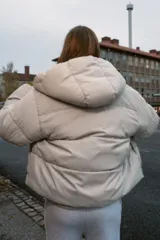 Anorak corto acolchado de Zara, color beige, con cuello subido, capucha, manga larga con puños elásticos y cierre frontal cruzado con botones magnéticos.