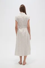Vestido camisero midi sin mangas, con cuello camisero, cierre frontal con botones, bolsillos en el pecho, cinturón de tela con lazo y estampado a rayas verticales en tonos beige y blanco.