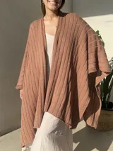 Ruana tejida en punto jersey, color negro con destellos brillantes de lurex. Presenta una etiqueta de cuero sintético con logo en la parte posterior.