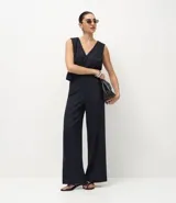 Pantalón de corte wide leg confeccionado en tejido punto roma, con diseño de raya de tiza, cintura estructurada, bolsillos delanteros y cierre frontal discreto.