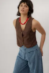 Chaleco de denim azul con cuello en V, cierre frontal con botones metálicos y pespuntes en contraste.