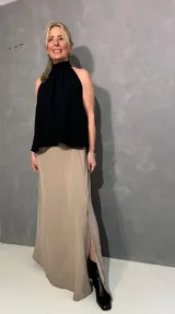 Falda larga beige de corte recto con tajo lateral, confeccionada en viscosa y elastano, con pretina lisa al frente y elástico en la parte posterior.