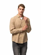 Camisa de franela color beige, de manga larga, con cuello camisero con botones de ajuste, bolsillo frontal y cierre de botones oscuros.
