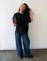Remera de algodón color negro, de corte holgado y manga corta, con un delicado detalle de encaje en el ruedo inferior.