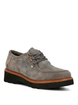 Zapatos de gamuza color gris de la marca Hush Puppies, modelo Renovo. Presentan diseño robusto con cordones gruesos, ojales metálicos, suela gruesa track y costuras pespunteadas en el borde.