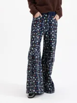 Pantalón de corte wide leg con diseño cargo, confeccionado en guipiure de denim azul con estampado floral. Presenta bolsillos laterales tipo cargo y cierre frontal.