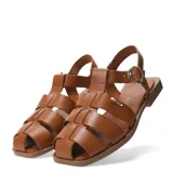 Sandalias franciscanas de cuero color marrón, con diseño de tiras cruzadas, punta cerrada y suela plana. Cuentan con cierre de hebilla metálica ajustable en el tobillo y detalle de aplique metálico con el logo de la marca.