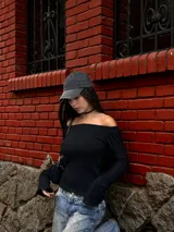 Sweater de punto trenzado color bordó, con escote estilo bote que deja los hombros al descubierto y mangas largas ligeramente acampanadas.