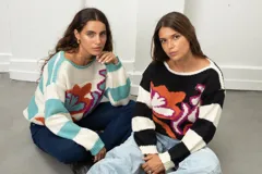 Buzo de tejido de punto con diseño estampado de flores abstractas y mangas a rayas. Presenta cuello redondo y corte holgado.