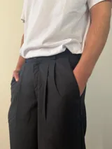 Pantalón sastrero de corte recto y holgado, color gris claro, con pinzas frontales y cintura con elástico posterior.