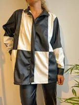 Campera con cierre frontal, diseño color block blanco y negro, cuello camisero y bolsillos laterales.