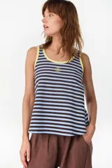Musculosa de corte holgado con diseño a rayas horizontales en tonos marrón y crudo. Presenta ribetes en color fucsia en el cuello redondo y en las sisas, además de un pequeño bordado decorativo en el centro del pecho.