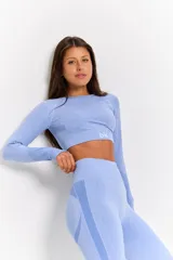 Conjunto deportivo de dos piezas compuesto por un top de manga larga con cuello redondo y calzas de tiro alto. Ambas prendas presentan un diseño seamless con detalles de textura en relieve y un acabado jaspeado en color azul cielo.