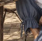 Pantalón azul deslizante de corte ancho, con cintura elástica y puños fruncidos ajustables mediante tiras atadas en los tobillos.