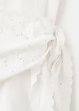 Vestido midi evasé color blanco, de cuello redondo y sin mangas con tirantes anchos. Cuenta con detalle de pañuelo bordado cruzado en la cintura.