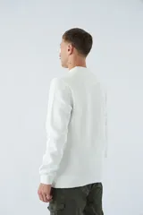 Buzo blanco de algodón con cuello redondo, mangas largas y logo y arte en relieve en el frente.