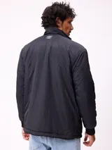 Campera reversible de sherpa y nylon, color negro, con cierre frontal, cuello alto y bolsillos frontales con solapa.