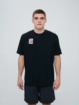 Remera de manga corta Umbro de color negro, corte holgado, con cuello redondo y pequeño parche estampado en el pecho que simula una estampilla.