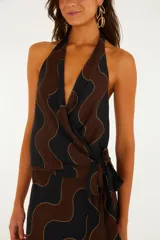 Top de escote halter con diseño cruzado, lazo lateral y estampado geométrico de ondas en tonos negro y marrón con líneas doradas.