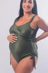 Malla enteriza maternal de textura acanalada en color verde militar. Presenta un diseño con escote cruzado, breteles regulables con herrajes metálicos y laterales con frunces ajustables mediante cordones. Posee espalda baja.