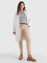 Pantalón chino color beige de sarga elástica, corte slim, con cierre de cremallera y botón, bolsillos traseros de ojal y logo de Tommy Hilfiger bordado en la parte trasera.